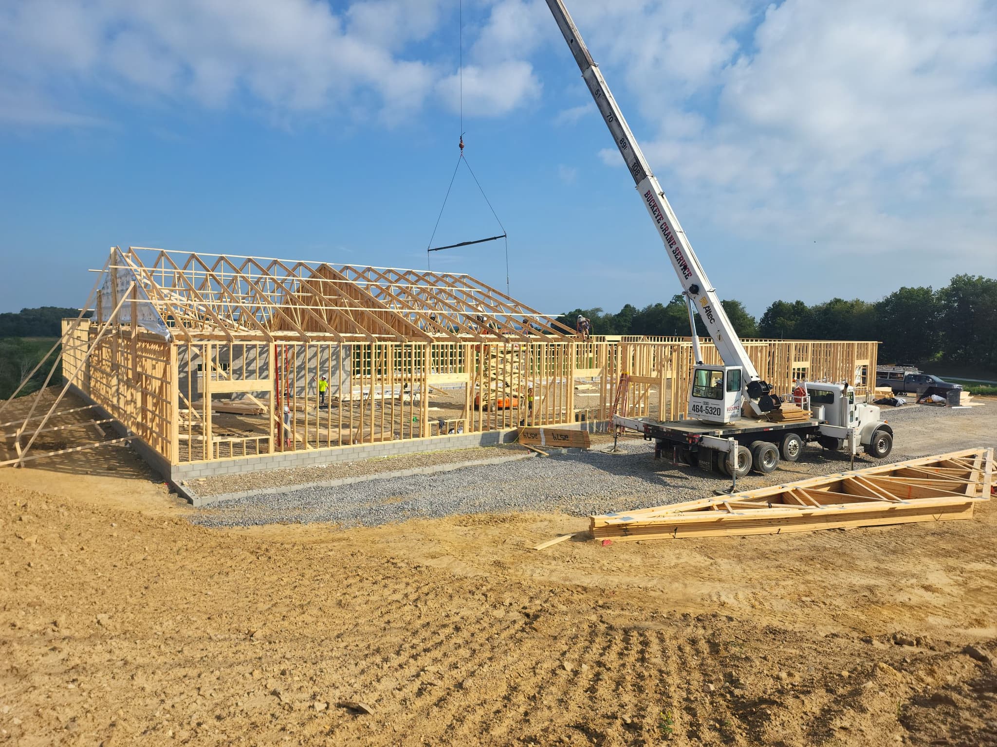 Buckeye Crane Service crane lifting roof trusses on a construction site