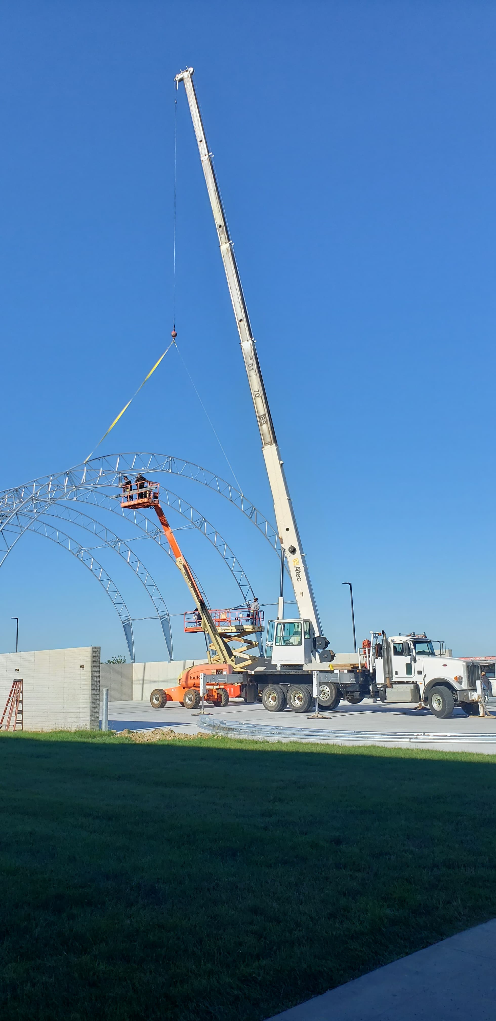 Crane lifting curved steel arches on a commercial building